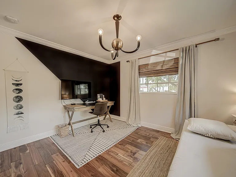 Bedroom has an antique retro chandelier with an accent design wall.