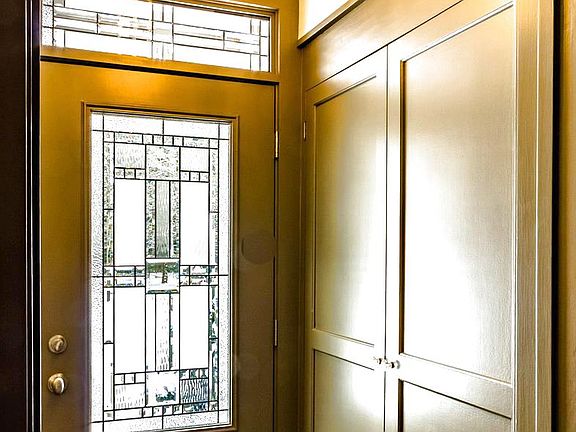 Beautiful front door with transom window in the foyer features Limestone flooring and crown molding.