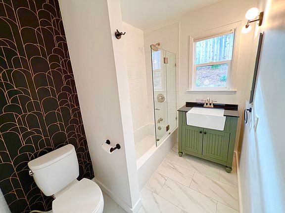 Updated shower with tub, glass enclosure, farmhouse sink and oak shelving