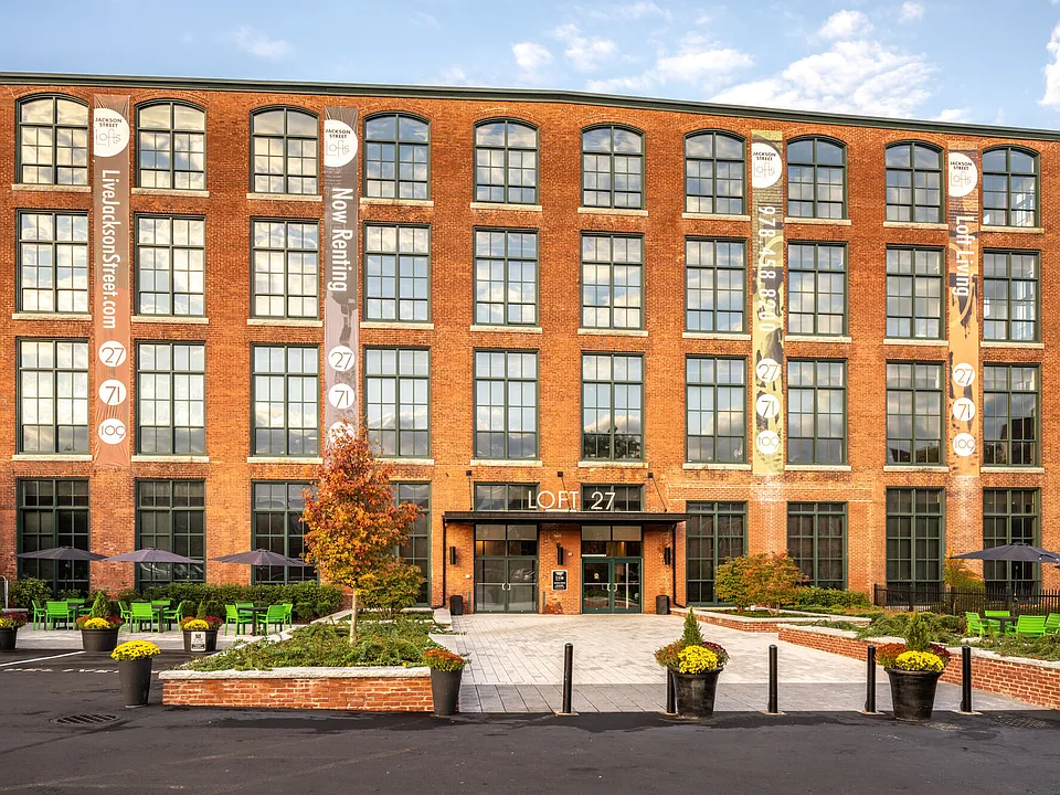 Apartment community entrance with brick exterior, landscaped grounds, and resident parking