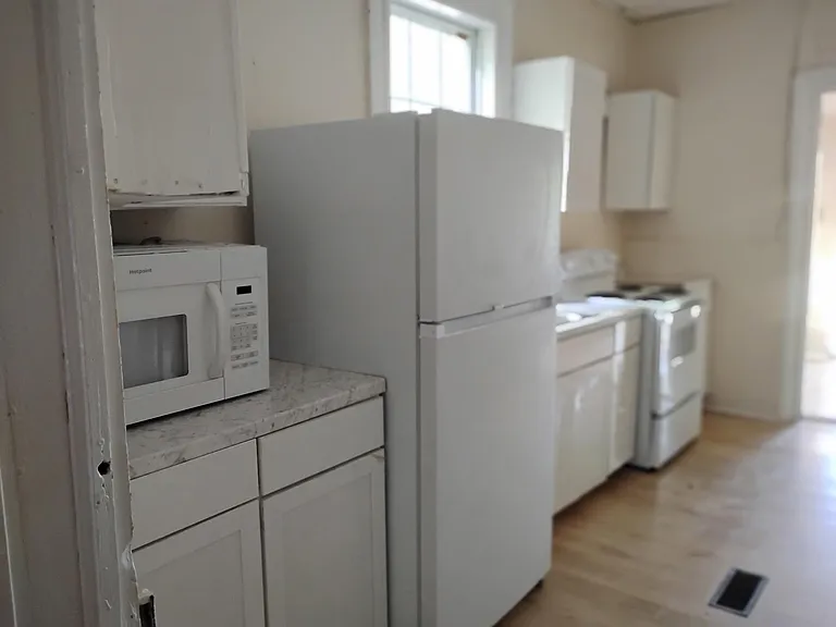 Galley kitchen with full-size refrigerator, microwave, and range, plus upper/lower cabinets for everyday storage.
