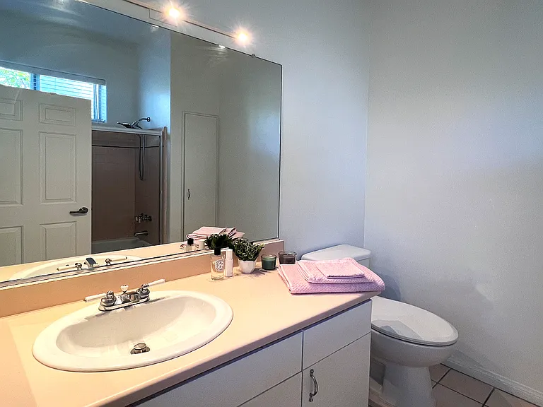 Modern second en-suite bathroom featuring a modern glass shower booth and soft, elegant light blush color tiles