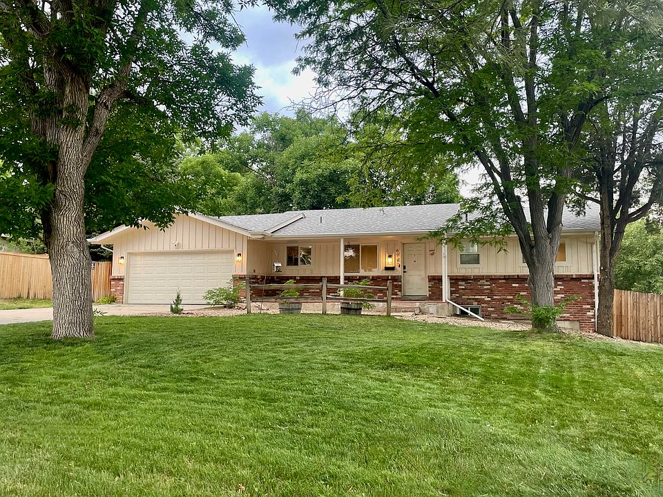 Front of house- spacious front yard with mature trees, large driveway and two car garage