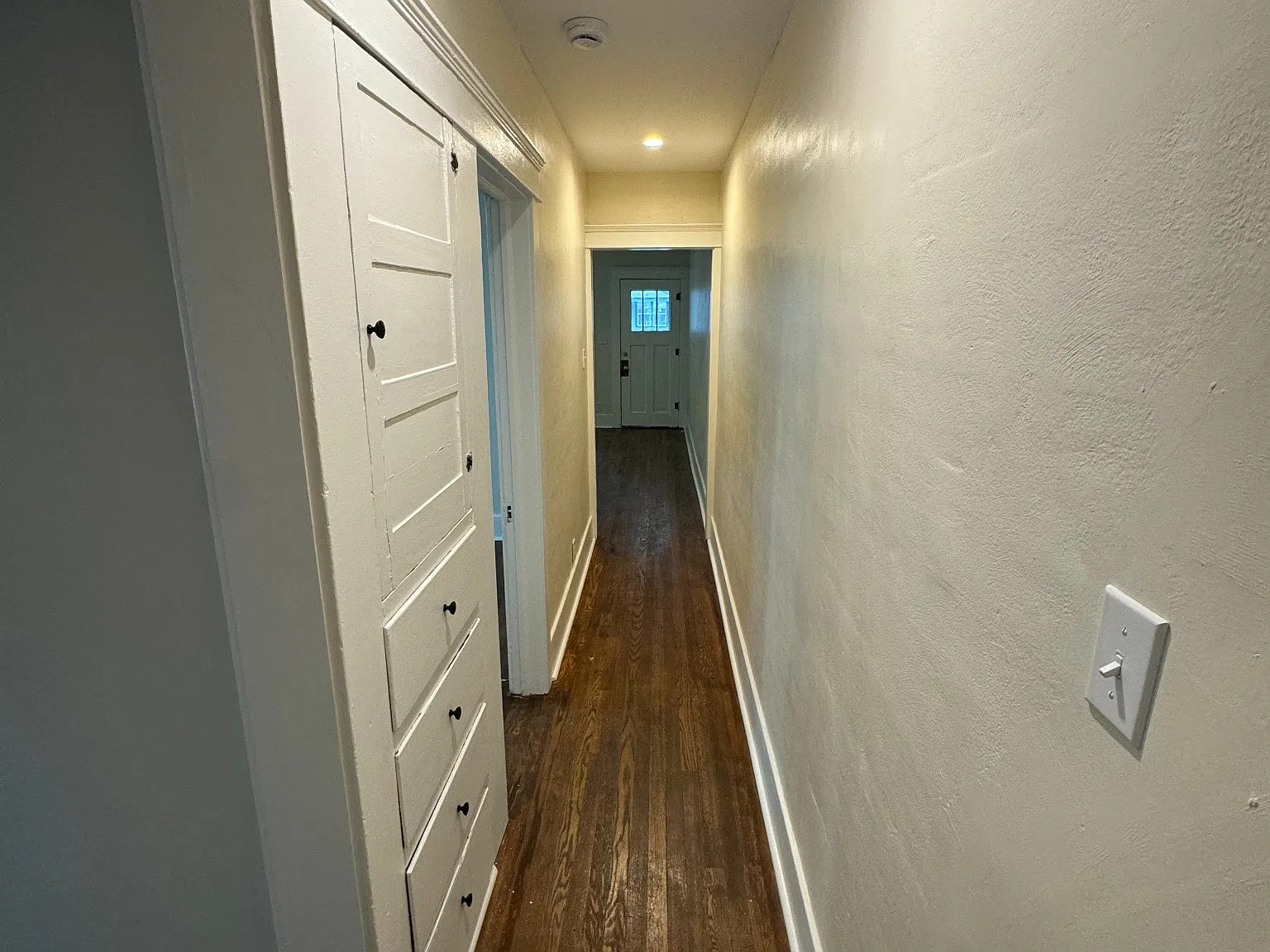 Hallway with built in storage. Primary bedroom to the left