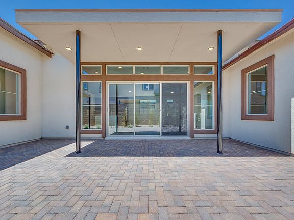 The image depicts a modern, well-designed building entrance with a paved brick walkway leading up to