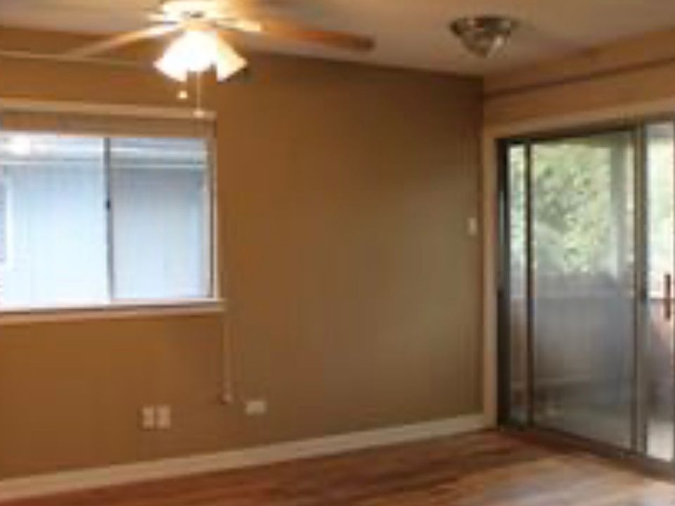 Living and dining area with ceiling fans. View to balcony