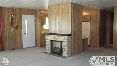 A lovely large living room with 'Faux' fireplace.  Light paneling makes everything seem open and large!