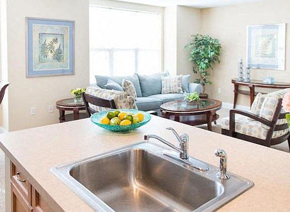 View of great room from kitchen showing large living area, bright windows, and part of dining area