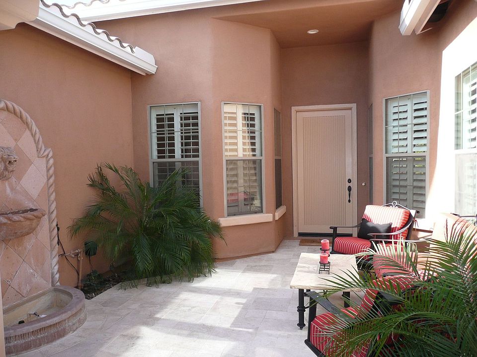 Lush courtyard entry with stone water fountain & travertine flooring.