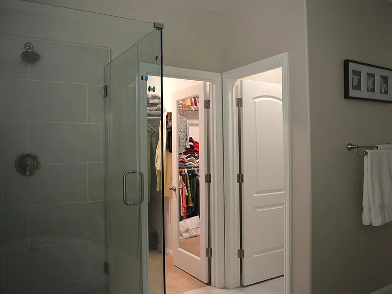 Primary Bathroom - the frameless shower, mirrored door to one of the 2 walk-in closets and door to the toilet room.
