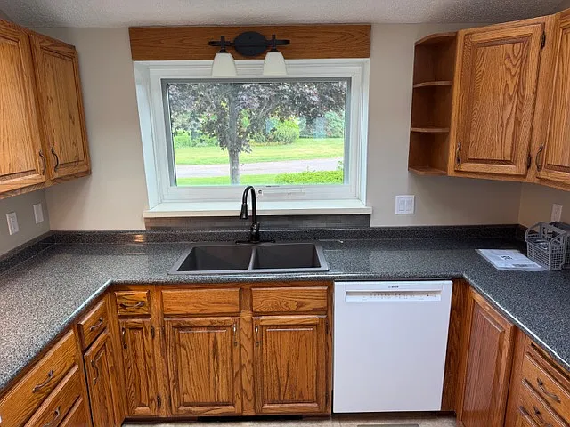Large window over sink looks out into front yard and plenty of green space