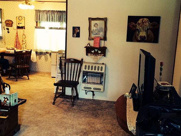 Living room from front door toward the dining area. The hallway to the 3 bedrooms & bathroom is just past the television. Wall gas heater was installed for electric outage.
