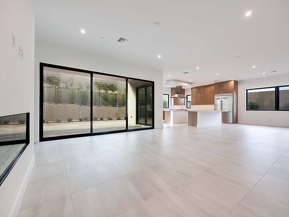 A spacious, modern interior with a large open floor plan, featuring wooden cabinetry, floor-to-ceili