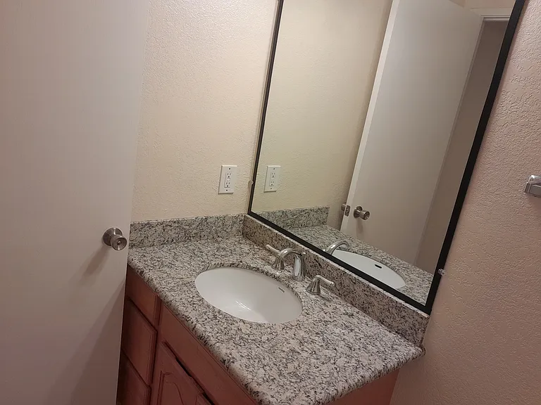 1/2 bathroom with marble countertop and tile floor