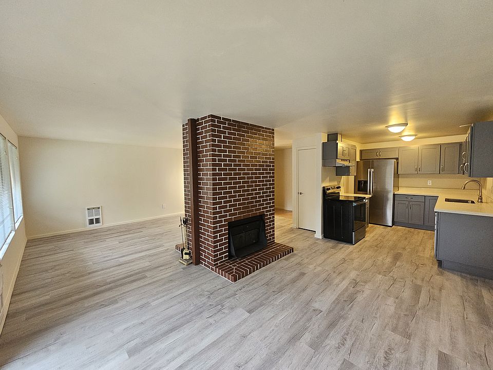 dining room with living room on the left of the fireplace. Coat closet and front entry are behind the fireplace to the right.