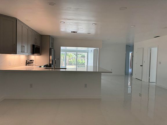 Another view of the kitchen and the back family room leading out to the sliding glass doors, large screened-in back porch, patio and backyard.