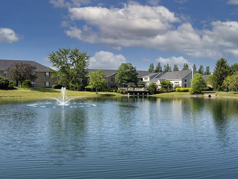 Relax by a picturesque lake, featuring a charming fountain and scenic homes that create a peaceful, inviting atmosphere.