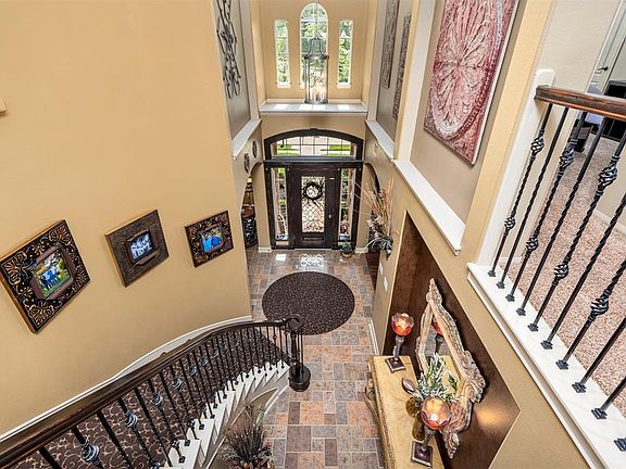 Another view of the foyer showing the picturesque front door, gorgeous high ceilings, art niches and updated lighting.