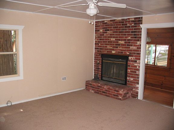 New carpeting and paint in living room w/fireplace and ceiling fan.