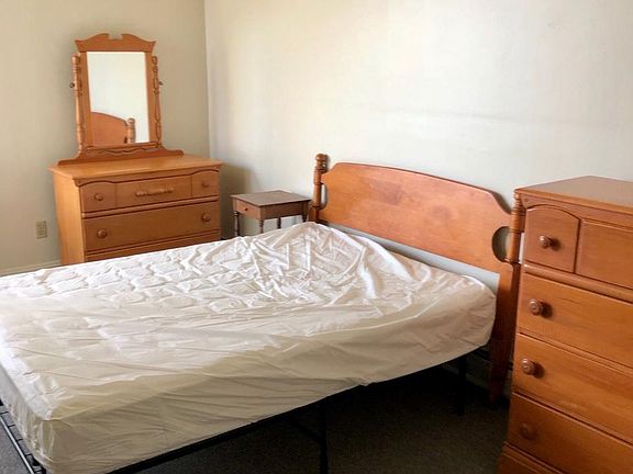 Furnished bedroom has bathroom on opposite wall and two closets.