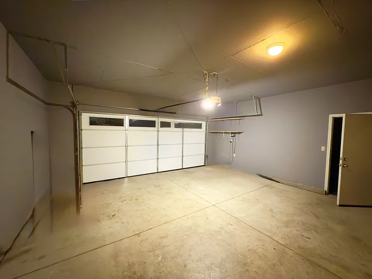Spacious garage with a fresh coat of paint and a brand-new door featuring windows for added natural light and style!