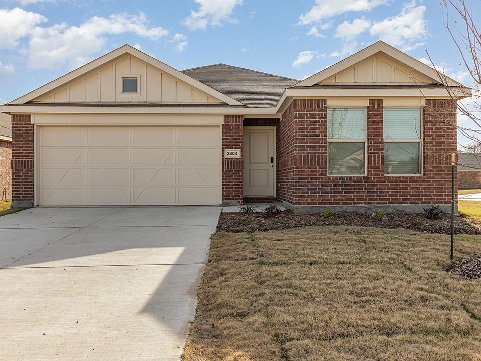 Ranch-style house featuring an attached garage, brick siding, and driveway