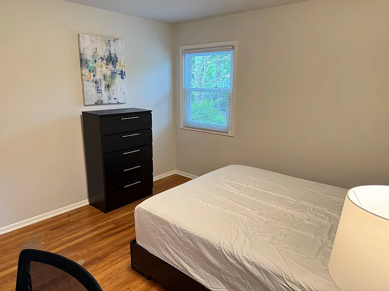 Private bedroom with hardwood floors, a window with blinds, and a dresser for convenient storage.
