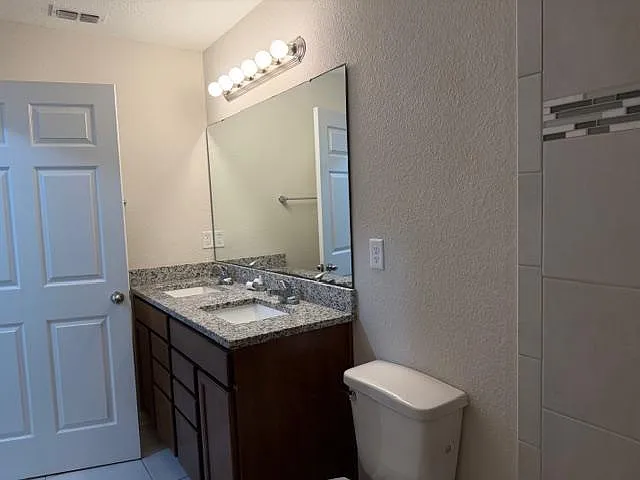 Well-appointed bathroom with dual-sink granite vanity, oversized mirror, and ample under-cabinet storage.