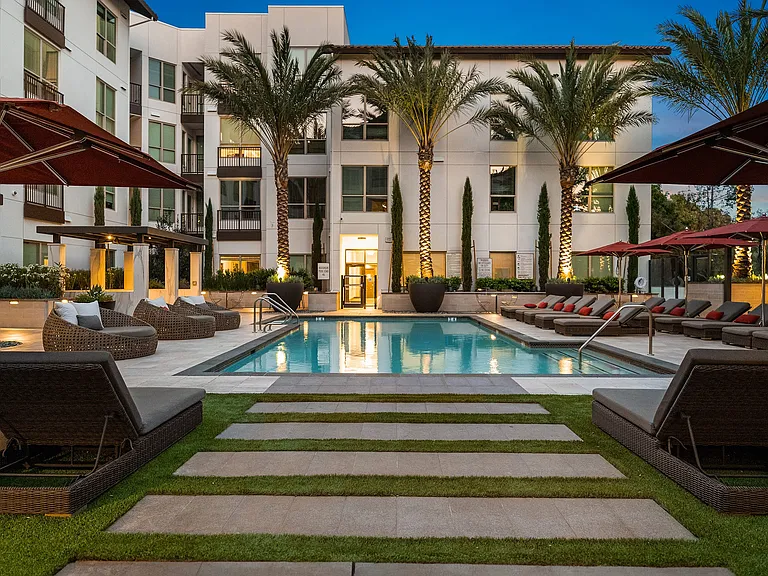 Evening pool deck with palm trees, cushioned loungers, and calm vibe