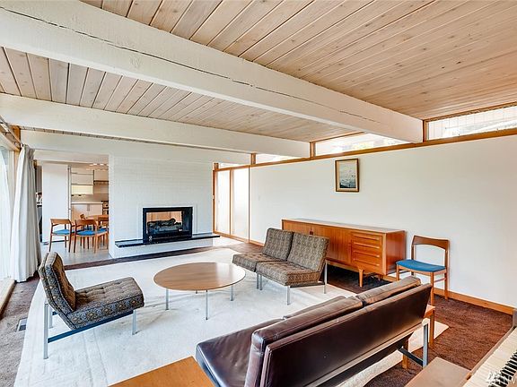 Open living room with a double sided gas fireplace separating the living room and kitchen area