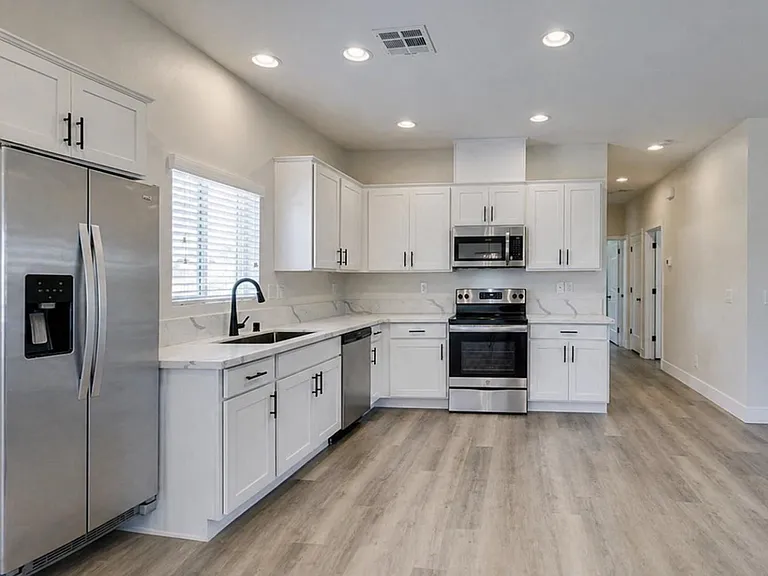 Spacious kitchen with ample white cabinetry, stone-look counters, and stainless steel appliances for everyday cooking.