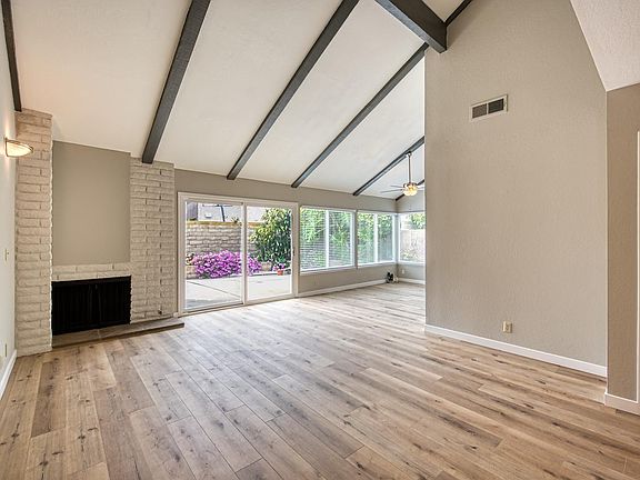 Living room with cozy fireplace and enhanced by vaulted beam ceiling.