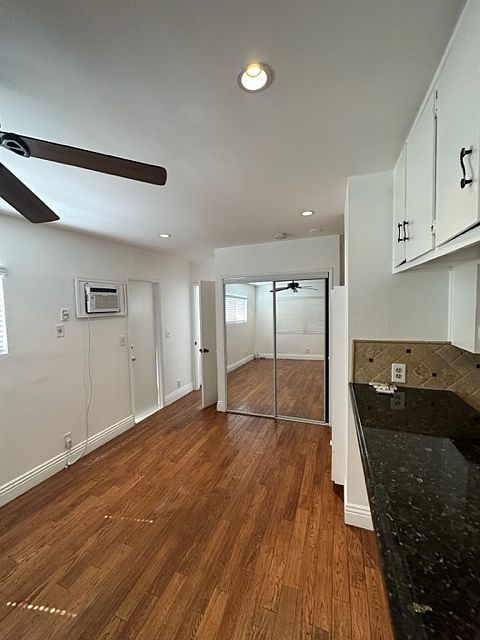 This is a view of your living room with the kitchen on the right side, and the mirrored closet at the far end, and slightly showing is your ceiling fan.