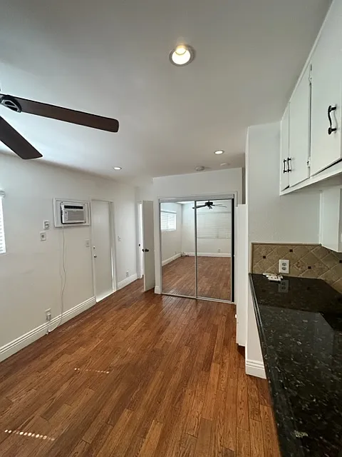 This is a view of your living room with the kitchen on the right side, and the mirrored closet at the far end, and slightly showing is your ceiling fan.