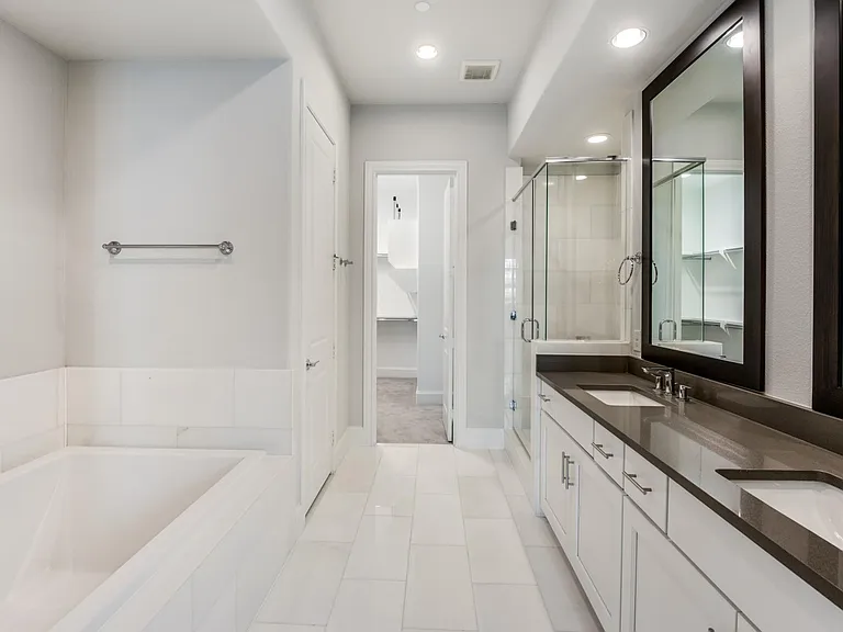 The drop-in tub might as well be a mini swimming pool, it's not your normal-sized tub. Double-vanity sinks lead to the walk-in shower, enclosed bathroom, and walk-in closet.