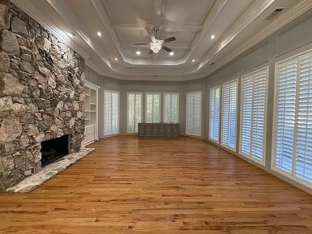 Unfurnished living room featuring a fireplace, light wood-type flooring, a ceiling fan, built in features, and ornamental molding