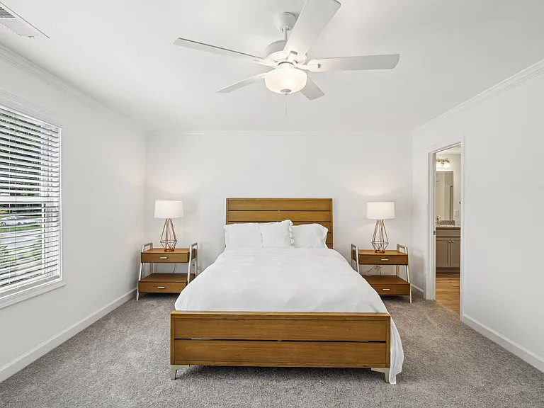 Another view of the spacious primary suite showcasing a grand bed and modern ceiling fan.