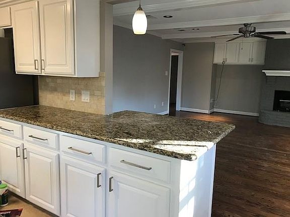 Updated kitchen with travertine tile opens up to the living area.