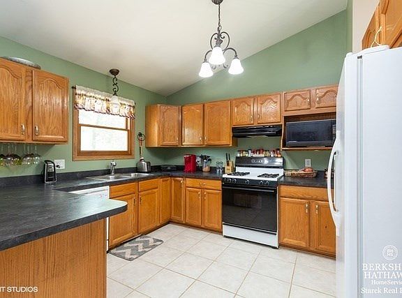 Updated Kitchen with newer cabinets, pantry, vaulted ceiling, breakfast bar, adjacent to dining area and living room. Views of lovely back yard.
