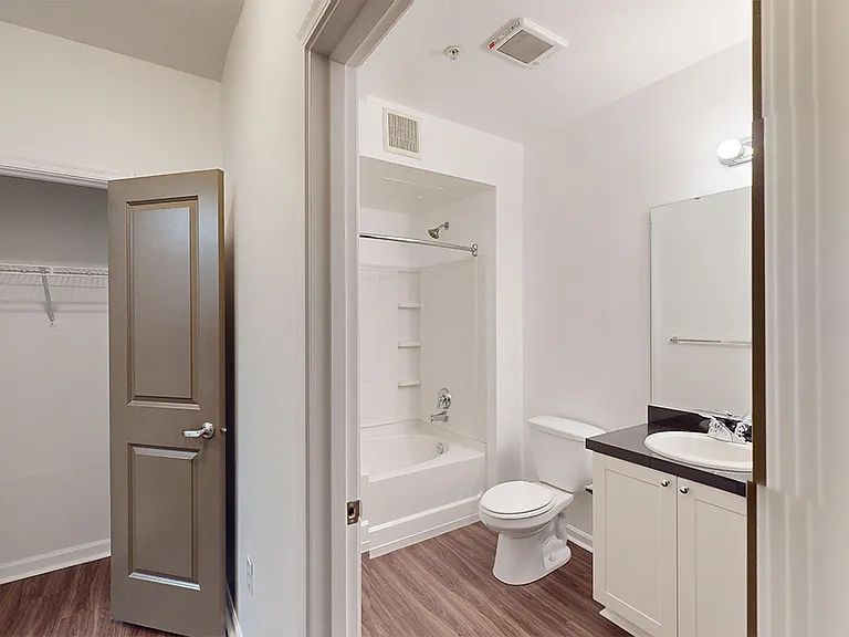 Apartment bathroom with large soaking tub and wood-style flooring.