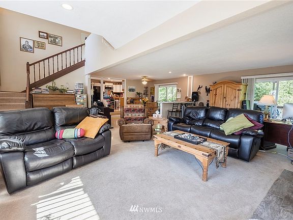 Large living room with stairs to the primary suite.  Current owner has an office set up in this generous space, as well as a piano and keyboard.  Acces to one of the decks through sliding doors in both living room and dining rooom.  You can see all the way to the kitchen from this far corner of the living room.