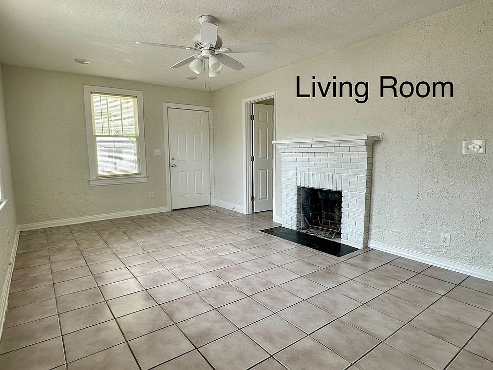 Bright and airy living room with large windows, easy-to-clean tile floors, and a decorative fireplace that gives the room a cozy touch.