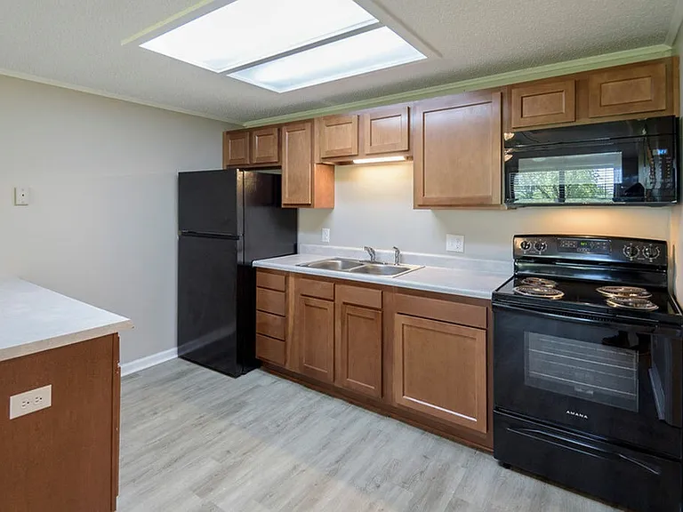 Kitchen with brown cabinets and black appliances, fully renovated
