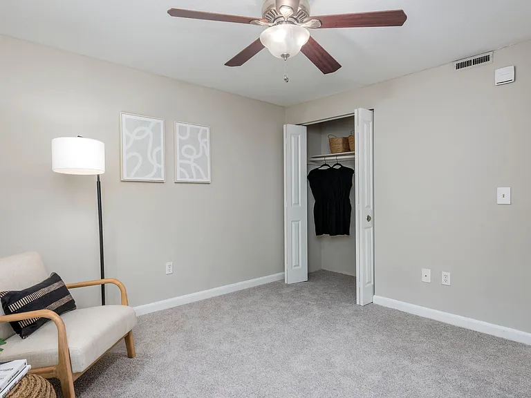 Your bedroom, a timeless space of elegance with plush carpeting, a ceiling fan, and a roomy closet.