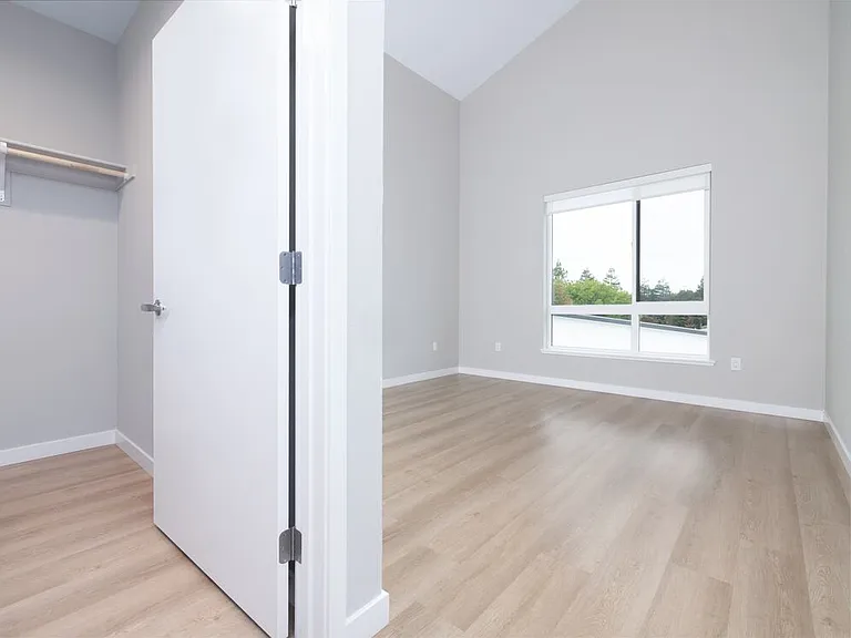 Signature Collection II Primary bedroom and walk-in closet with hard-surface vinyl plank flooring