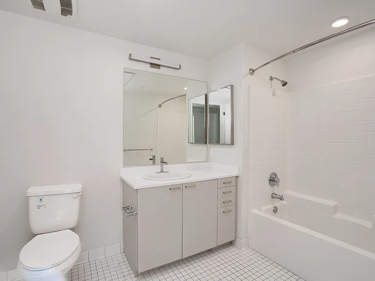 Bathroom B with bright tile flooring, a sleek vanity, and a full bathtub.