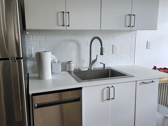 Section of the kitchen with stainless refrigerator and apartment-sized dishwasher.