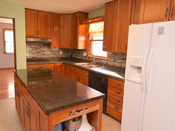 Beautiful cherry cabinetry with granite island, back splash and new tile floor