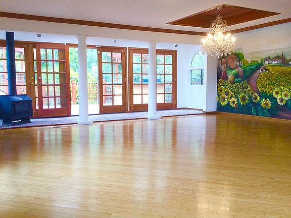 doors to back deck, wood burning stove and dining room area with hand painted mural