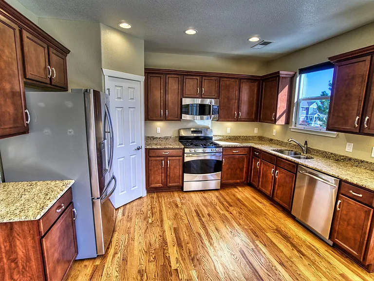 Main level - kitchen w/pantry, like-new stainless steel appliances, under-cabinet lighting, hardwood floors, and granite counter tops (14' x 11').